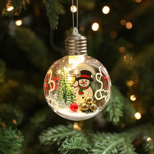 Clear Christmas bulb ornament with snowman and LED light hanging on a tree branch