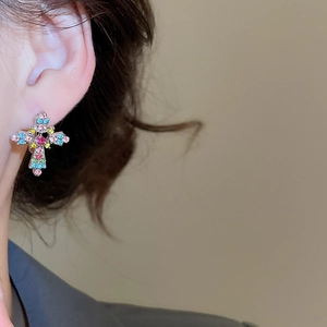 Detail of cross earrings featuring colorful rhinestones and a central pink gem