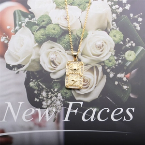 Elegant gold necklace with rectangular sun and lightning pendant over white rose background