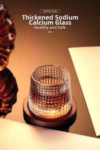 Macro shot of whiskey glass with textured lattice design and dark brown wood coaster