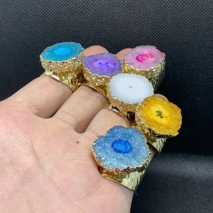 Detalle de anillos anchos bañados en oro de 14K con piedras de cristal druzy coloridas