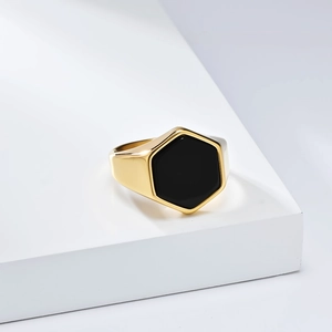 Macro view of gold hexagonal signet ring with black stone inlay on a white pedestal