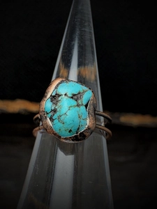 Macro shot of turquoise stone on handmade adjustable copper ring on cone display stand