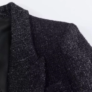 Detail of black tweed blazer showing metallic thread texture and collar stitching