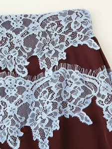 Dettaglio del tessuto satinato bordeaux con pizzo floreale azzurro e bordi a ciglia
