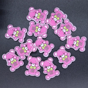 Flat lay of pink resin bear charms with Hug Me text for DIY phone case crafts