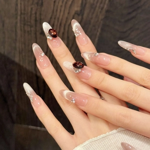 Pink cat-eye press-on nails with red gemstone accents and micro pearls in almond shape