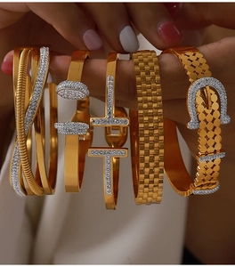 Macro shot of assorted gold-plated titanium bracelets with paved diamonds and T-shape detail