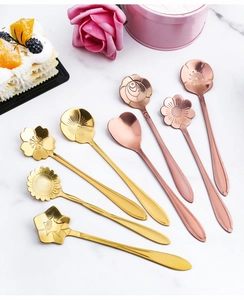 Close-up of flower and heart shaped gold stainless steel spoons on marble