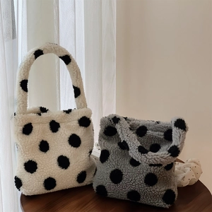 Détail de mini sacs à main en peluche à pois blancs et gris sur une table en bois
