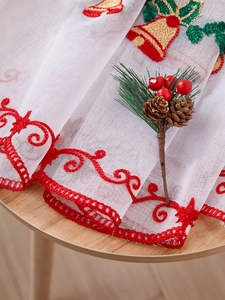 Detail of Christmas snowflake embroidery on white mesh fabric with red bells pattern