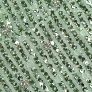 Macro shot of sage green sequins and plum-shaped rhinestone embroidery on mesh fabric