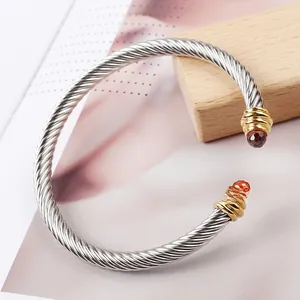 Macro detail of silver cable twisted bracelet with gold ends and red gemstone inlays