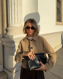 Detail of camel suede jacket with large pockets and stylish leather bag accessory