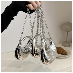 Gros plan de trois mini sacs métalliques argentés avec textures lisses et martelées