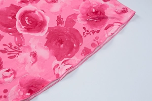 Close-up of pink floral fabric showing rose print texture and detailed overlock stitching
