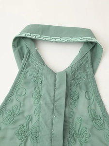 Détail du haut vert dos nu avec broderie papillon délicate et liseré décoratif élégant