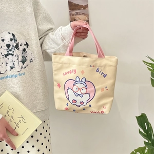 Detailed view of beige canvas tote bag featuring a cartoon rabbit print and pink handle