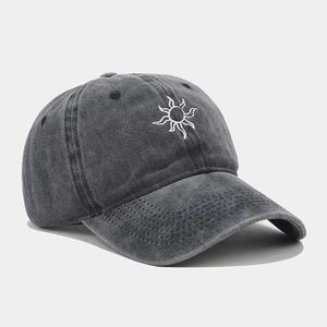 Close-up of sun embroidery detail on dark gray washed cotton baseball cap texture