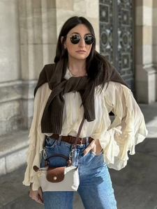 Fashionable cream ruffled layered V-neck shirt with jeans and brown knit sweater