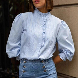 Detail von eleganten Puffärmeln und zarten Rüschen an einer hellblauen Bluse