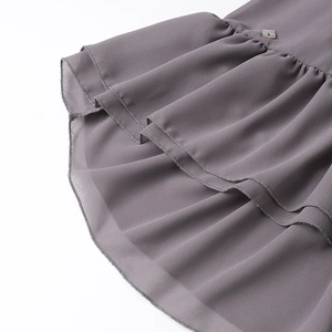 Dettaglio dell'orlo grigio a balze con bordo delicato e bottone quadrato decorativo