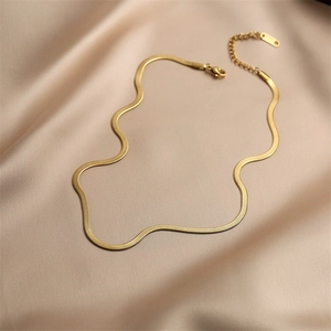 Close-up of golden flat snake chain necklace with lobster clasp on luxury satin fabric