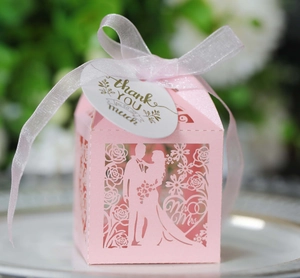 Detail of pink laser-cut wedding favor box with Mr & Mrs motif and satin ribbon tag