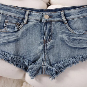 Detail der Distressed-Denim-Shorts mit ausgefransten Kanten und hochwertigem Metallknopf