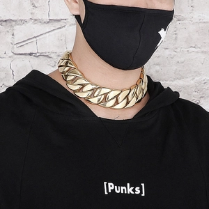 Close-up of a chunky gold Cuban link chain necklace worn on a model in street style