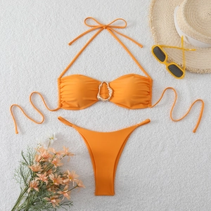 Detail of vibrant orange bikini featuring a gold metal ring and textured pleats