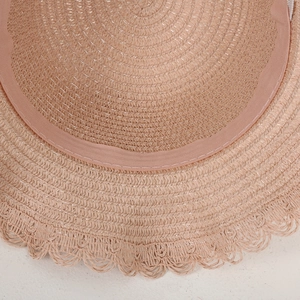 Macro detail of the interior sweatband and woven straw texture of a pink sun hat