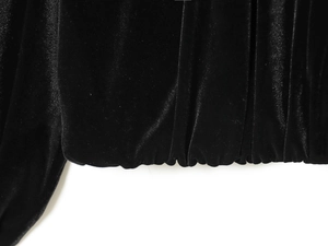 Detailaufnahme des elastischen Saums und des glänzenden schwarzen Samtstoffs der Bomberjacke