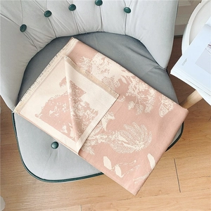 Écharpe rose effet cachemire avec motifs floraux et franges sur une chaise grise