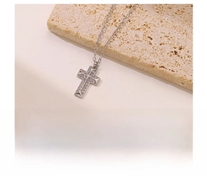 Macro shot of silver cross pendant with micro-pave zircons on textured stone