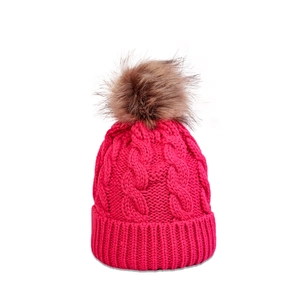 Detailed cable knit pattern on rose red beanie with a large faux fur pom-pom topper