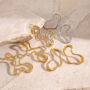Close-up of irregular wavy titanium steel earrings in gold and silver on natural stone