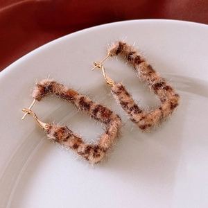 Close-up of leopard print velvet rectangular earrings on a white ceramic plate