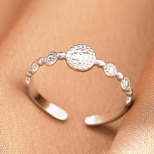 Detail of silver bohemian open ring with matte hammered finish and circular relief patterns