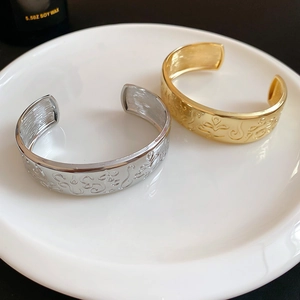 Close-up of gold and silver oval open bangles with vintage embossed floral patterns