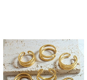 Top view of layered gold open rings on a textured stone surface with minimalist design