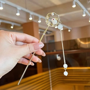 Close-up of golden hair pin with white rabbit design and long pearl tassel detail