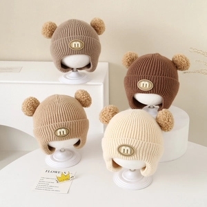Toddler winter knit earflap hat with double pom-poms in warm earth tones