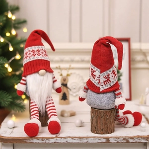 Pair of Christmas faceless gnomes with knitted hats sitting on wooden logs for decor