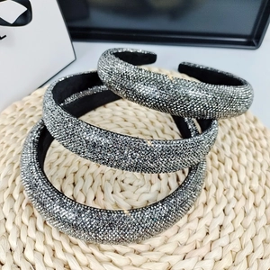 Stack of three braided wide headbands with sparkling dark silver rhinestones on woven mat