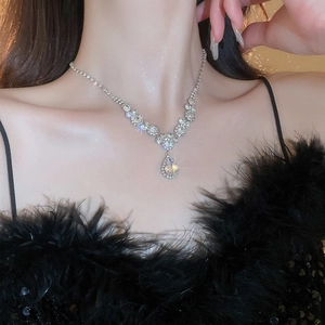 Close-up of sparkling silver V-shaped waterdrop crystal necklace worn by a female model