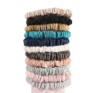 Set of 12 premium 22 momme silk scrunchies in various colors stacked on white background