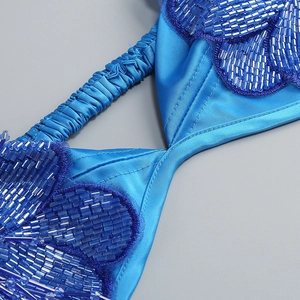 Détails macro de robe en satin bleu avec fleurs perlées et bretelles plissées