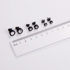 Three pairs of black Roman numeral stud earrings with zircons shown with a measuring ruler