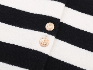 Macro detail of black and white striped knit fabric with embossed gold anchor buttons